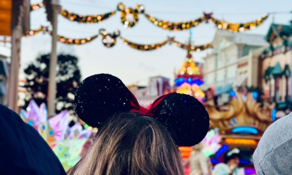 The back of a woman's head wearing Mickey ears at a Disney park